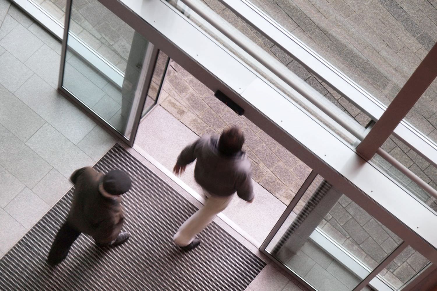 Bild zeigt: Zwei Männer verlassen einen Eingangsbereich