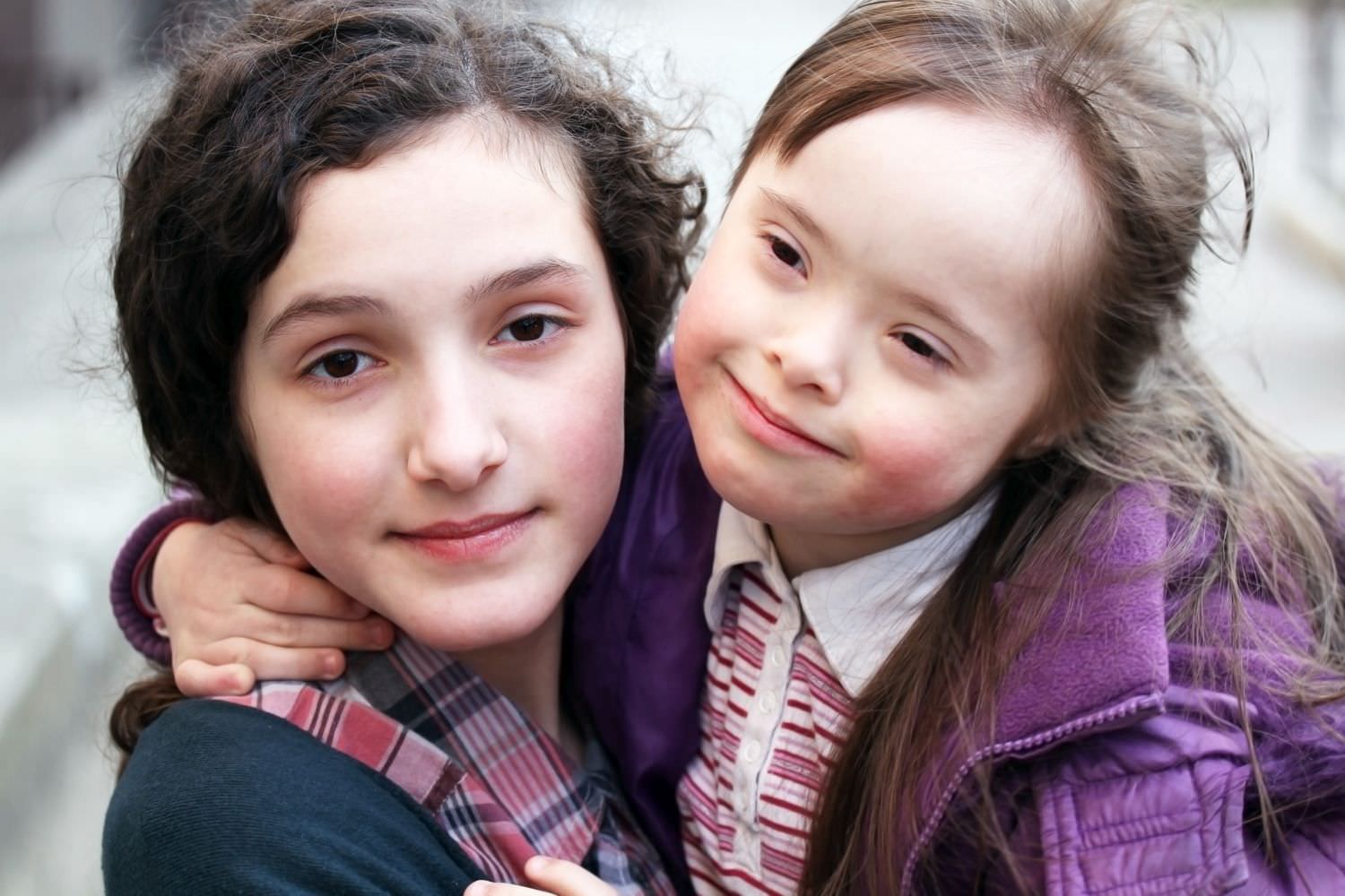 Bild zeigt: Ein Mädchen mit Down-Syndrom umarmt ihre Integrationshelferin