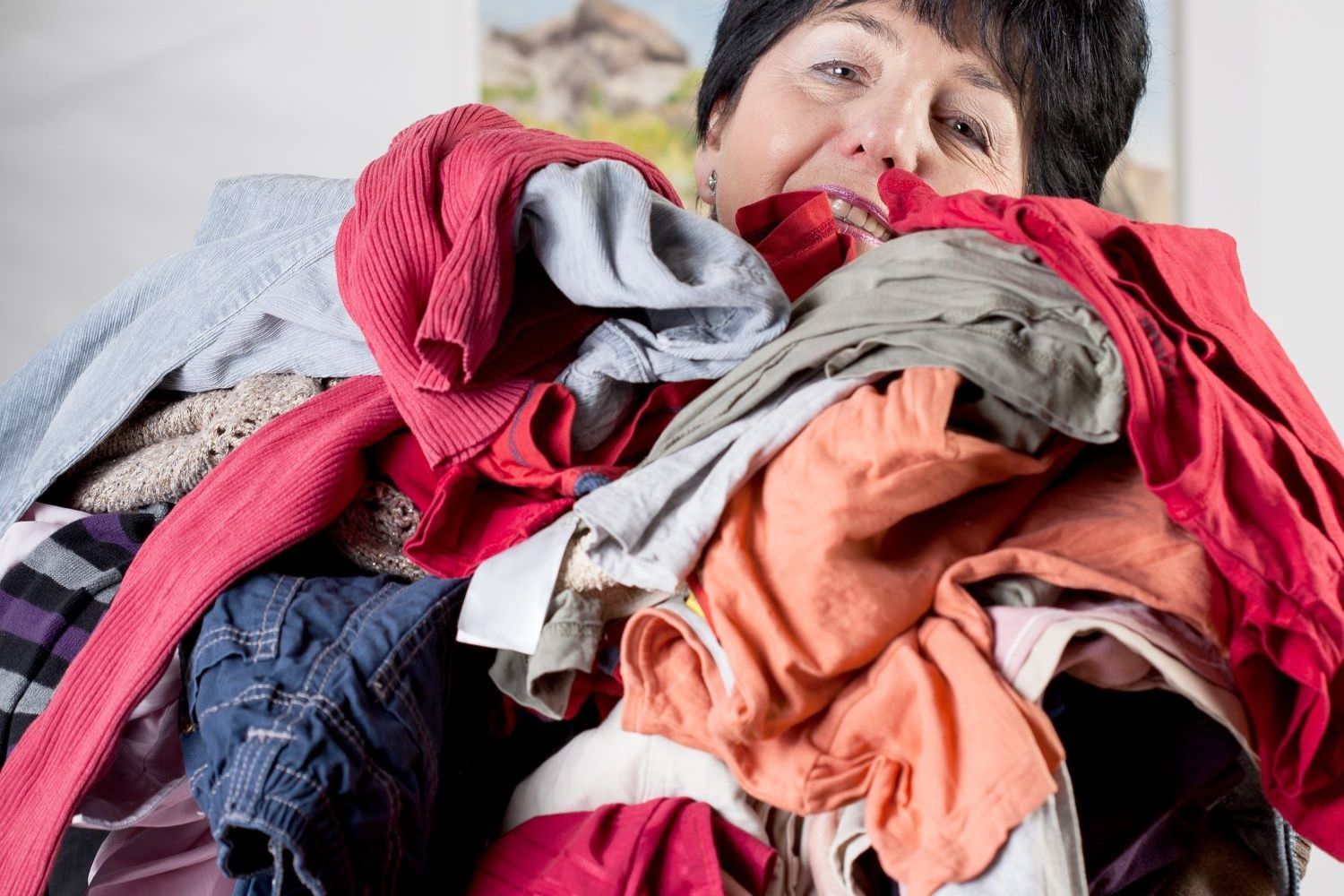 Bild zeigt: Ältere Frau trägt einen Haufen von Wäsche