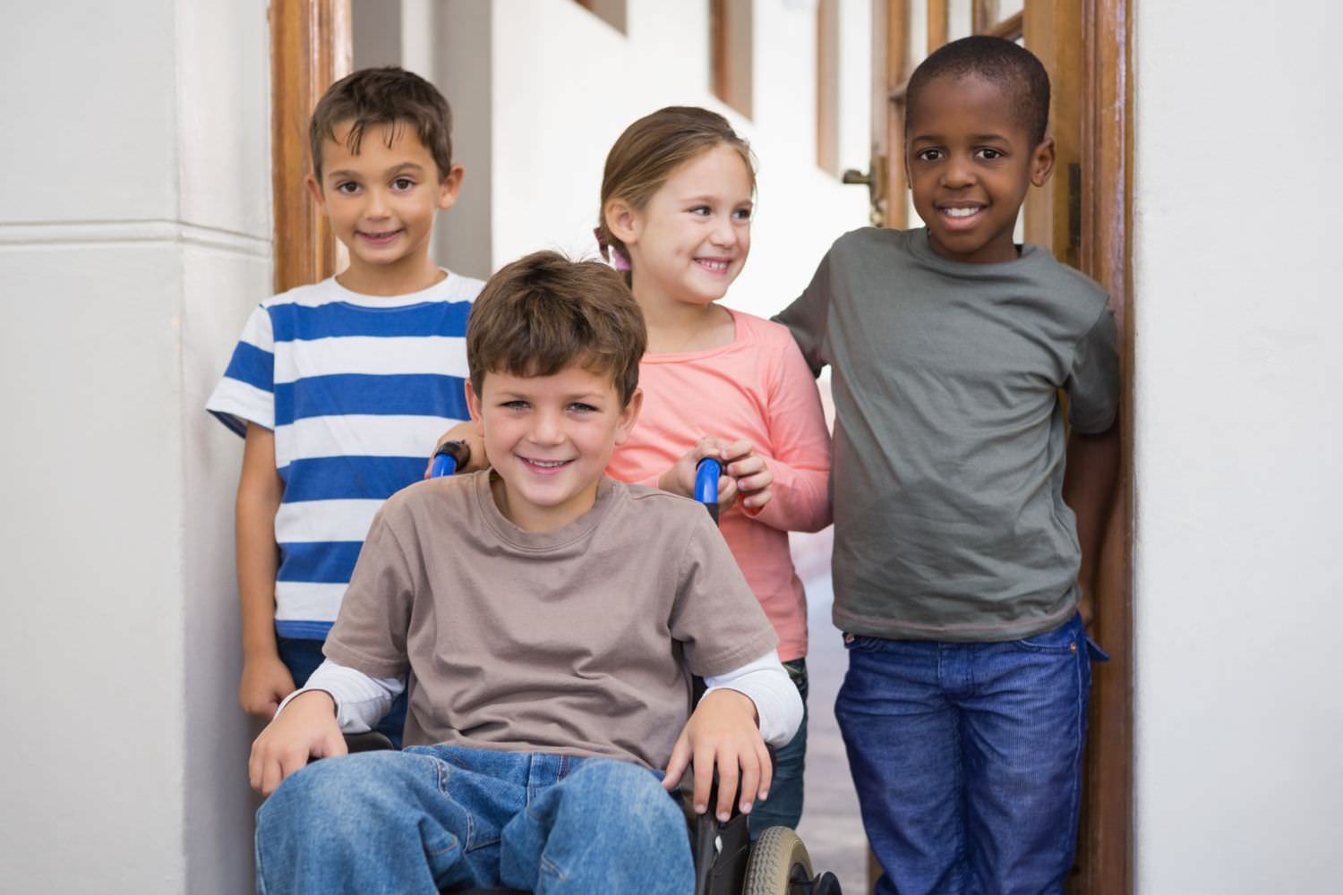 Bild zeigt: Drei Kinder unterschiedlicher Herkunft zusammen mit einem Jungen im Rollstuhl