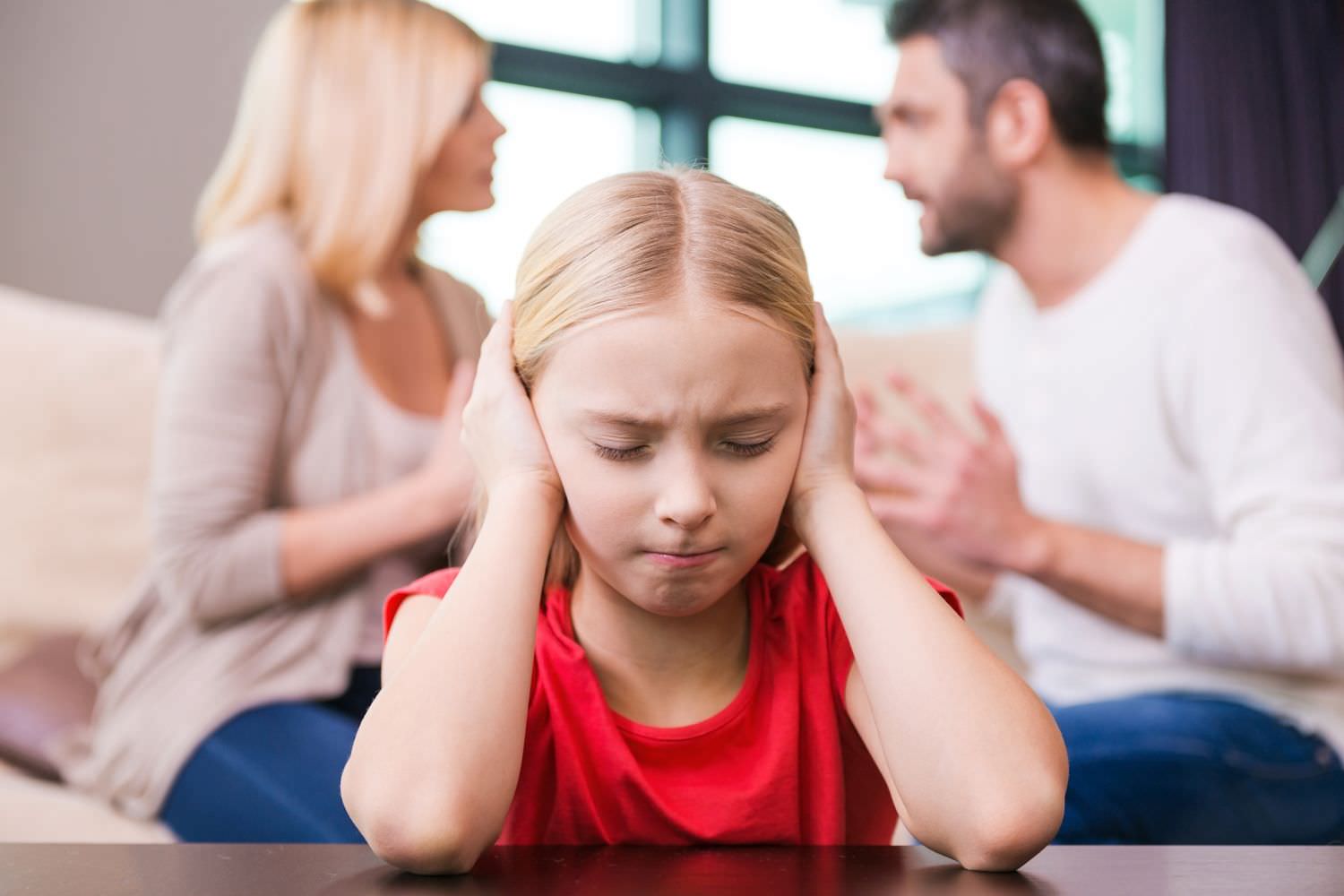 Bild zeigt: Ein Mädchen will nichts sehen und hören während die Eltern streiten