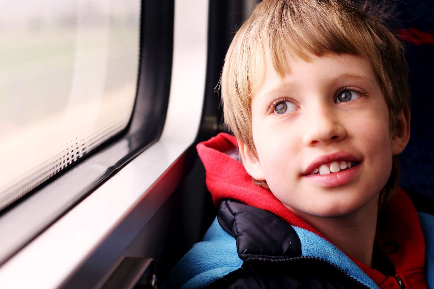 Bild zeigt: Junge sitzt nachdenklich am Fenster in einem Zug