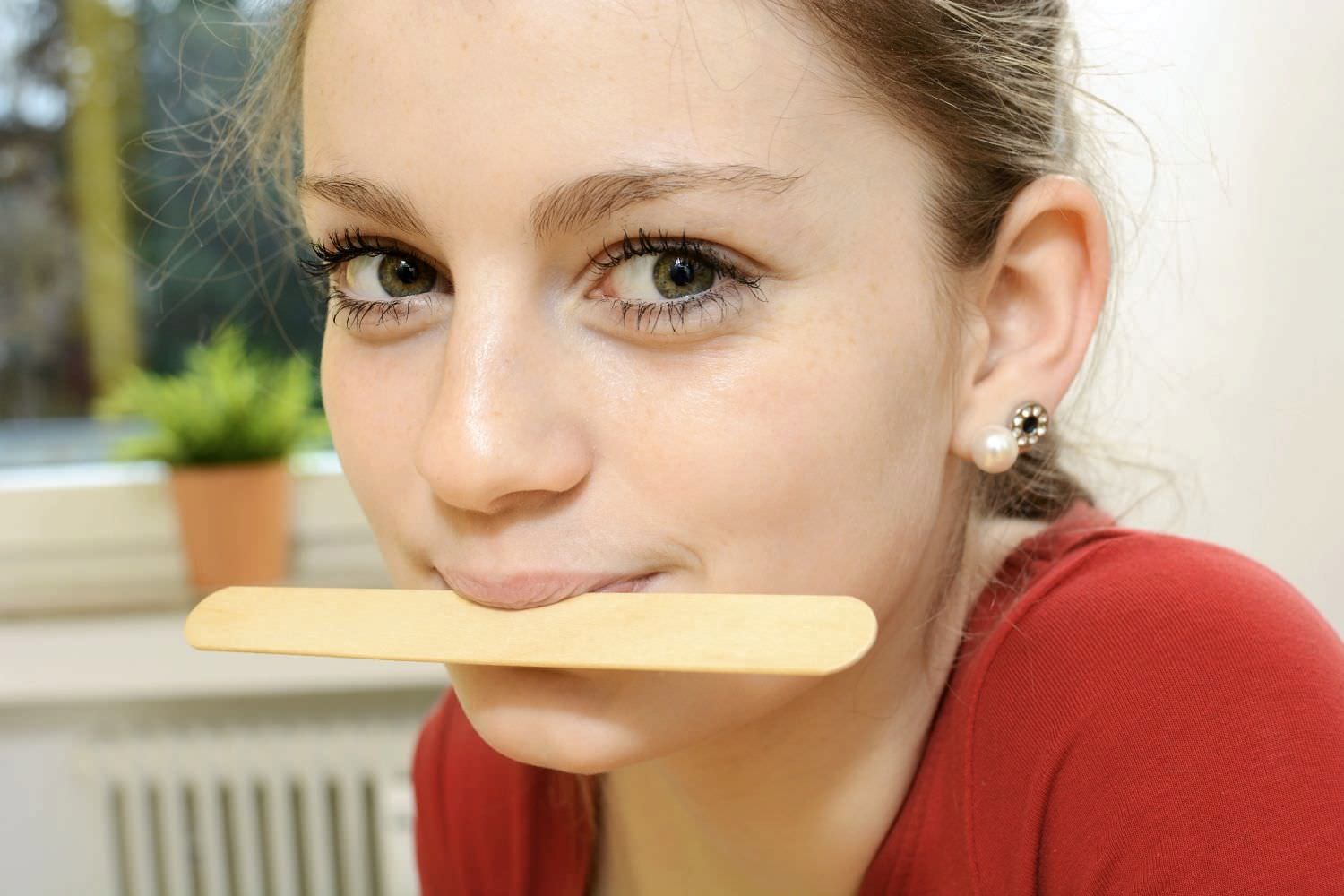 Bild zeigt: Junges Mädchen mit Holzstab zwischen den Lippen gepresst