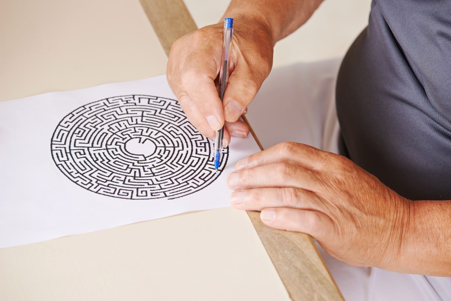 Bild Zeigt: Alter Mann malt in einem Labyrinth auf Papier
