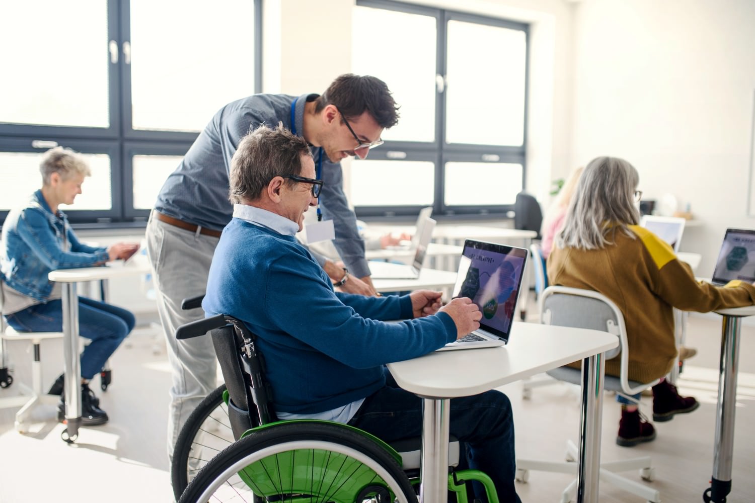 Bild zeigt: Ein älterer Mann sitzt in einem Rollstuhl am Tisch vor einem Laptop