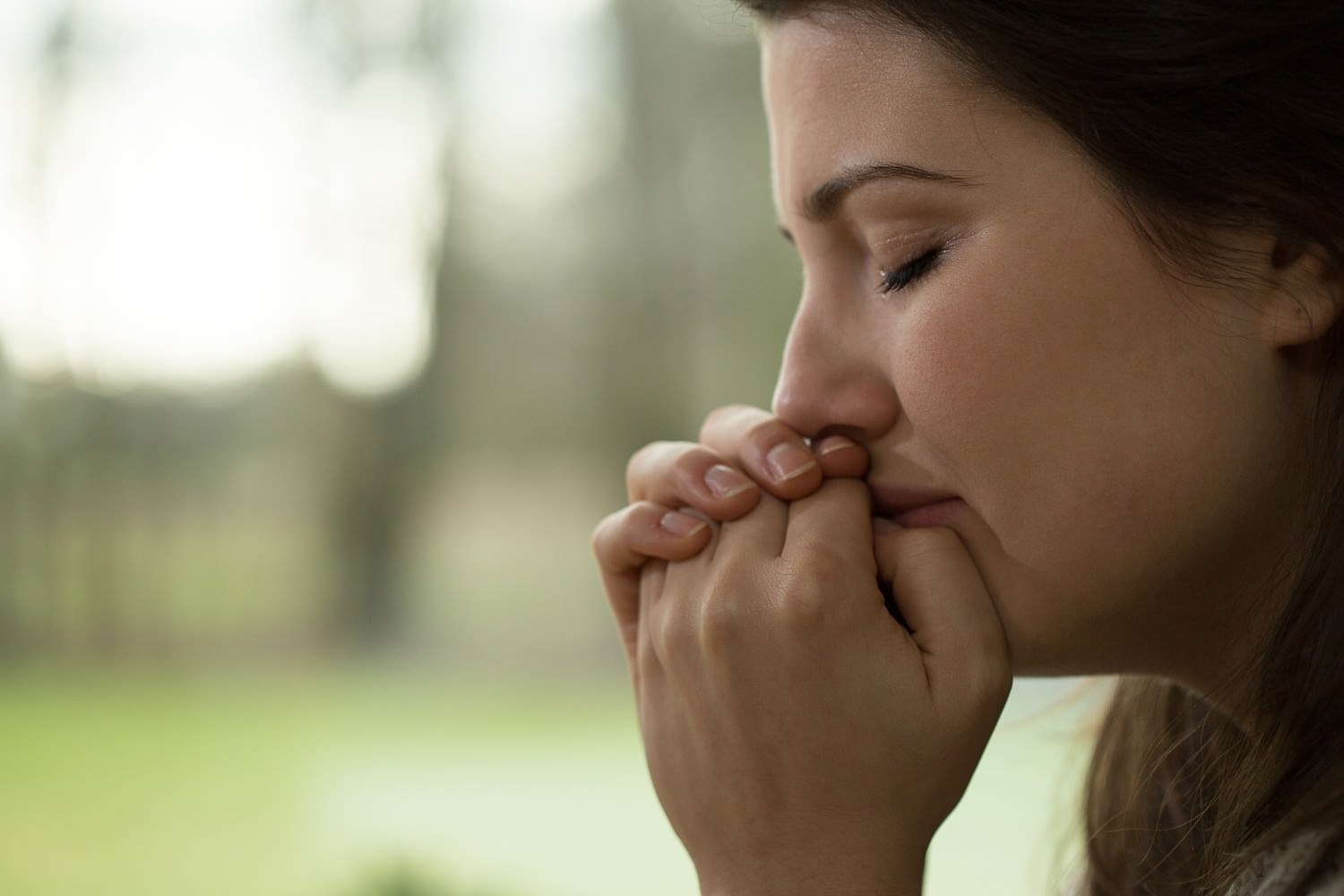 Bild zeigt: Verzweifelte, traurige, junge Frau mit geschlossenen Augen