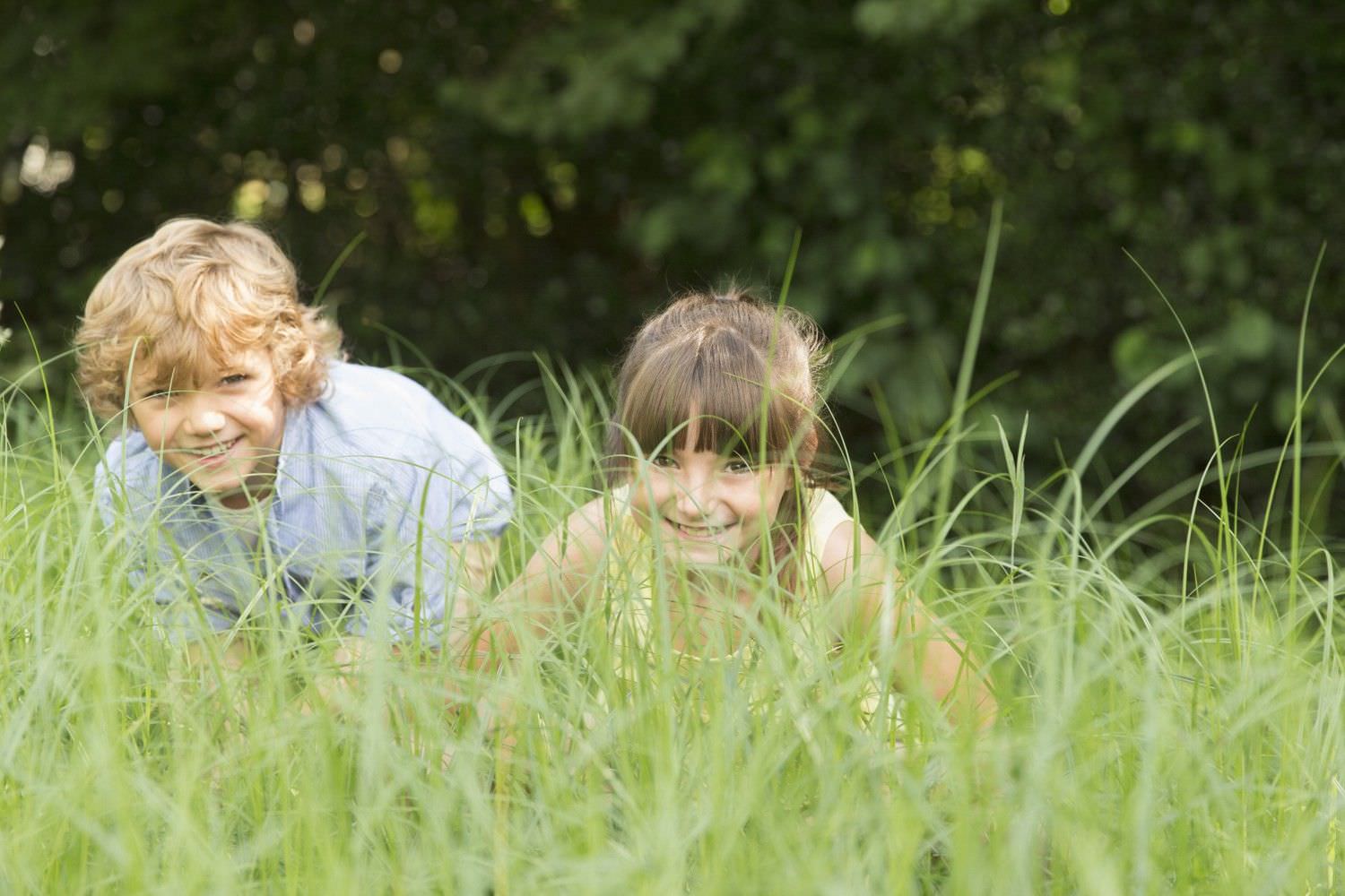 Bild zeigt: Junge und Mädchen verstecken sich im hohen Gras