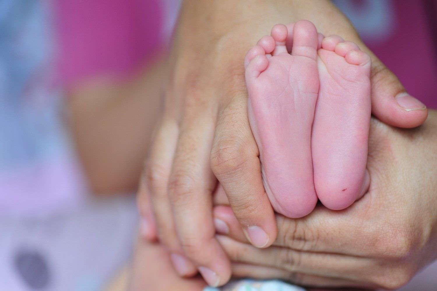 Bild zeigt: Zwei Hände umgreifen Säuglingsfüße
