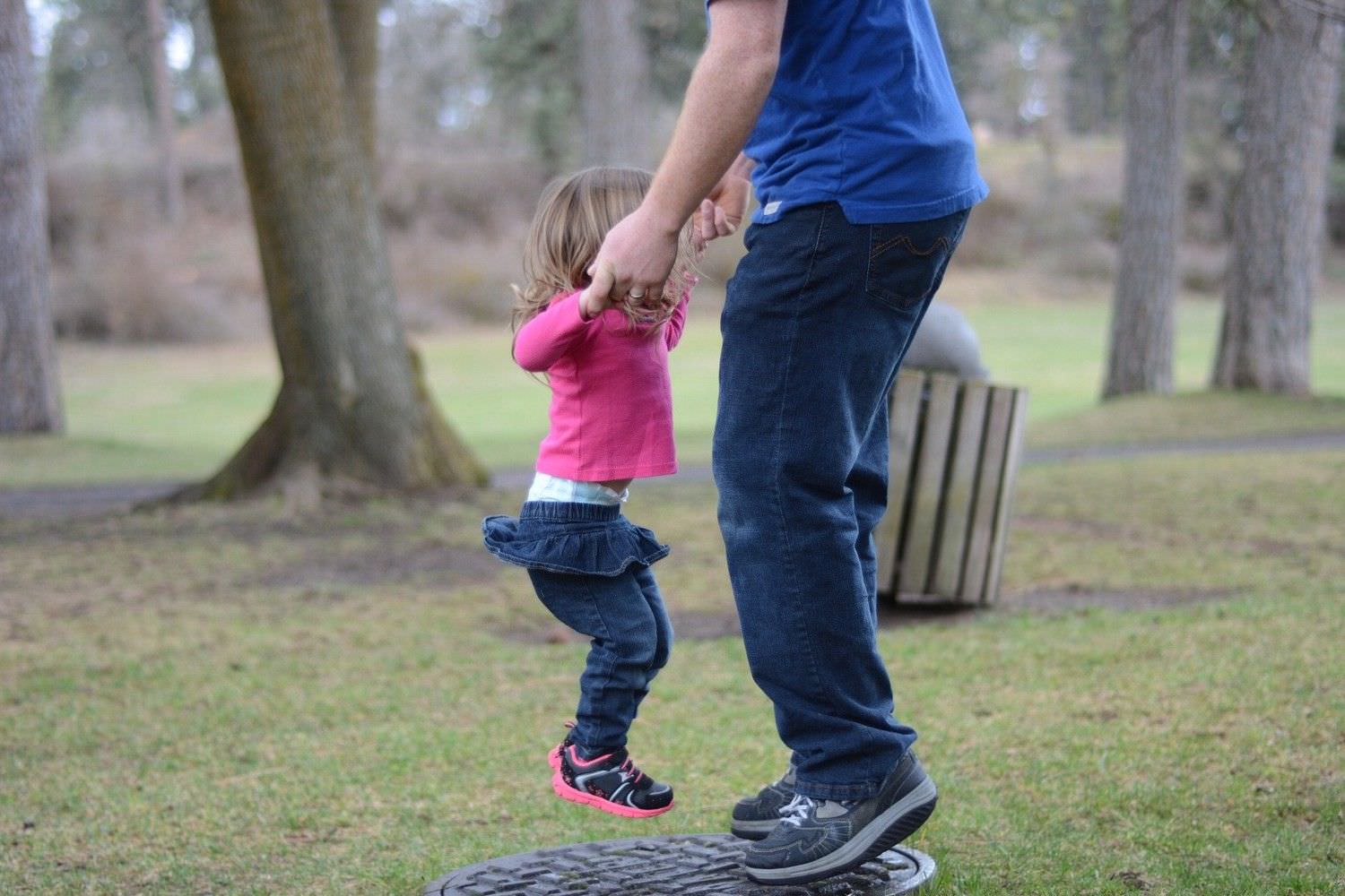 Bild zeigt: Vater mit kleiner Tochter auf dem Balancekissen im Park