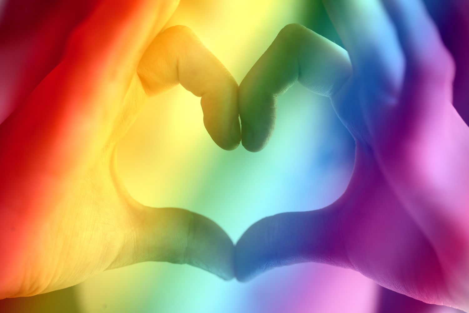 Bild zeigt: Zwei Hände formen ein Herz vor Regenbogenfarben