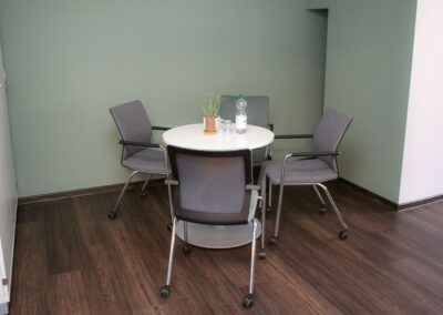 Bild zeigt: Besprechungsraum mit rundem Tisch und vier grauen Stühlen