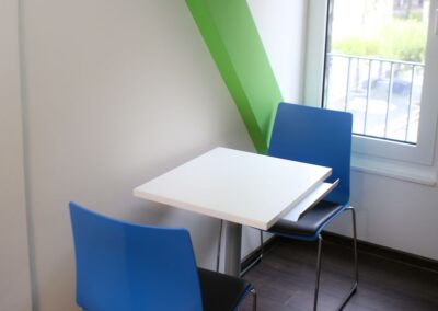 Bild zeigt: Besprechungstisch mit zwei blauen Stühlen im Arztzimmer