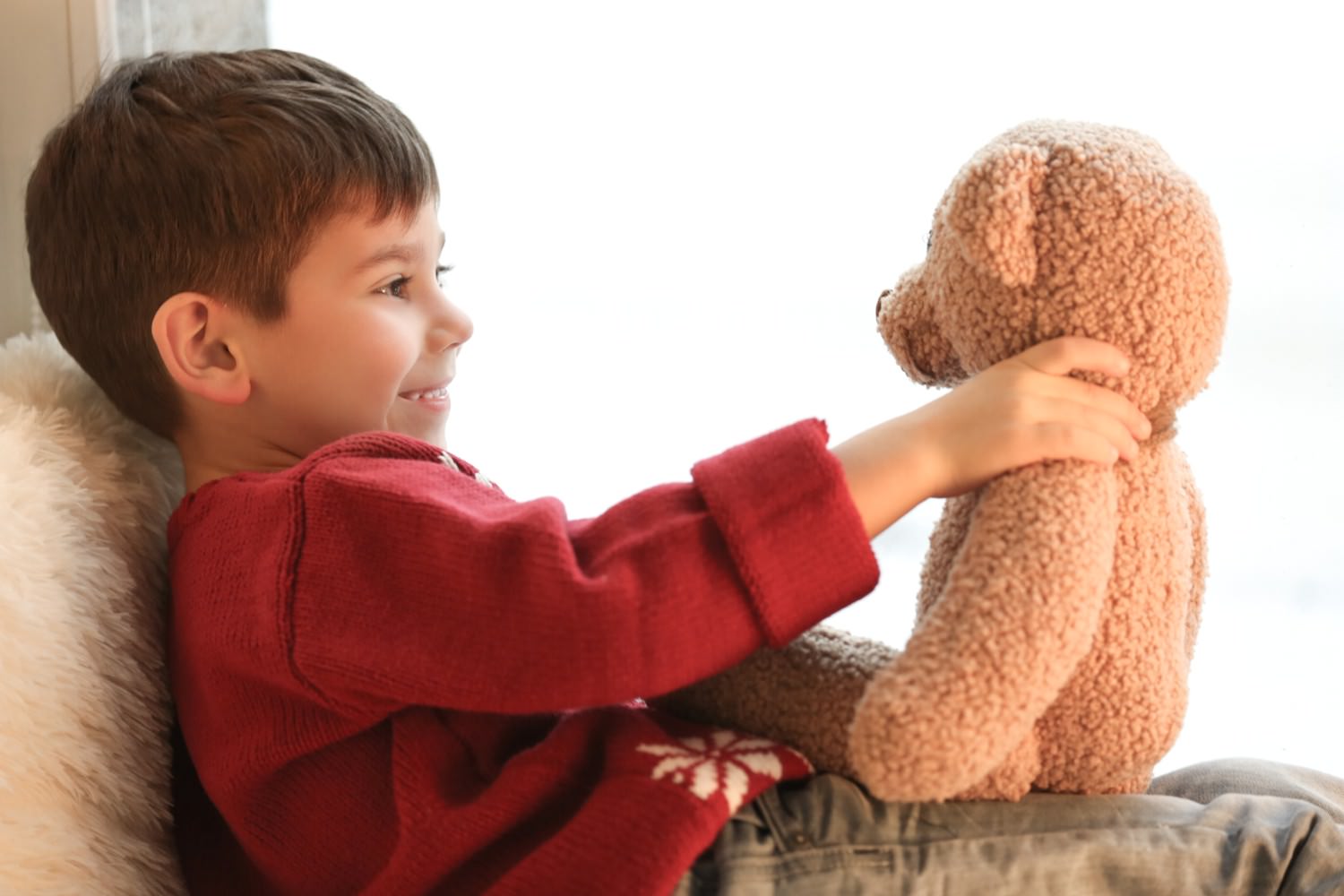 Bild zeigt: Kleiner Junge lacht mit seinem Teddybär