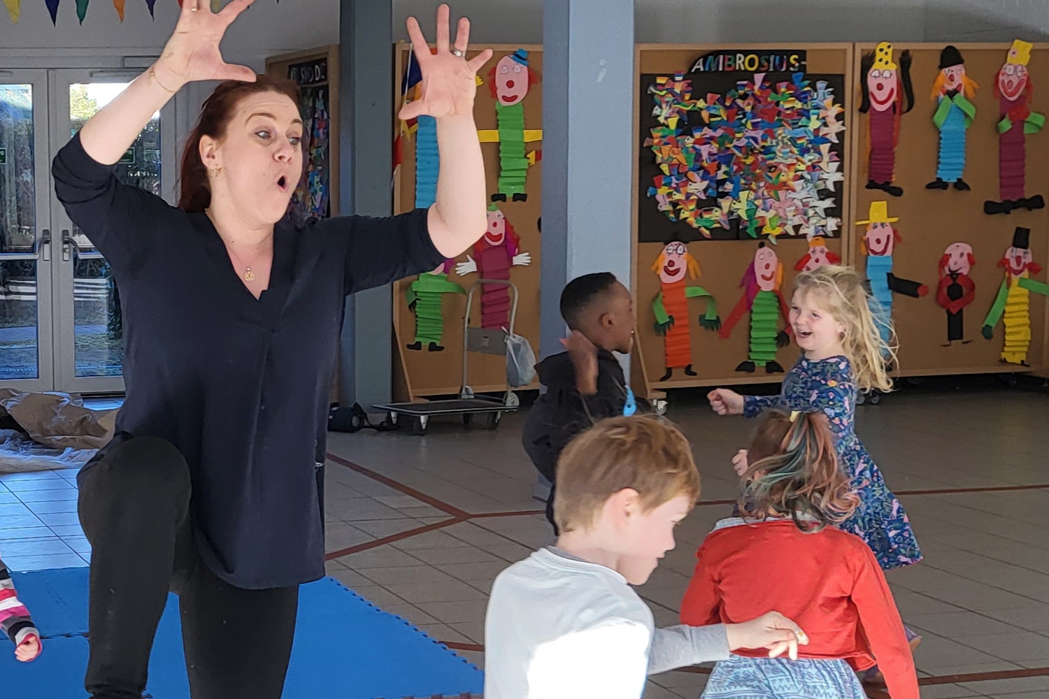Bild zeigt: Frau mit erhobenen Händen tanzt im Kreis mit Kindern
