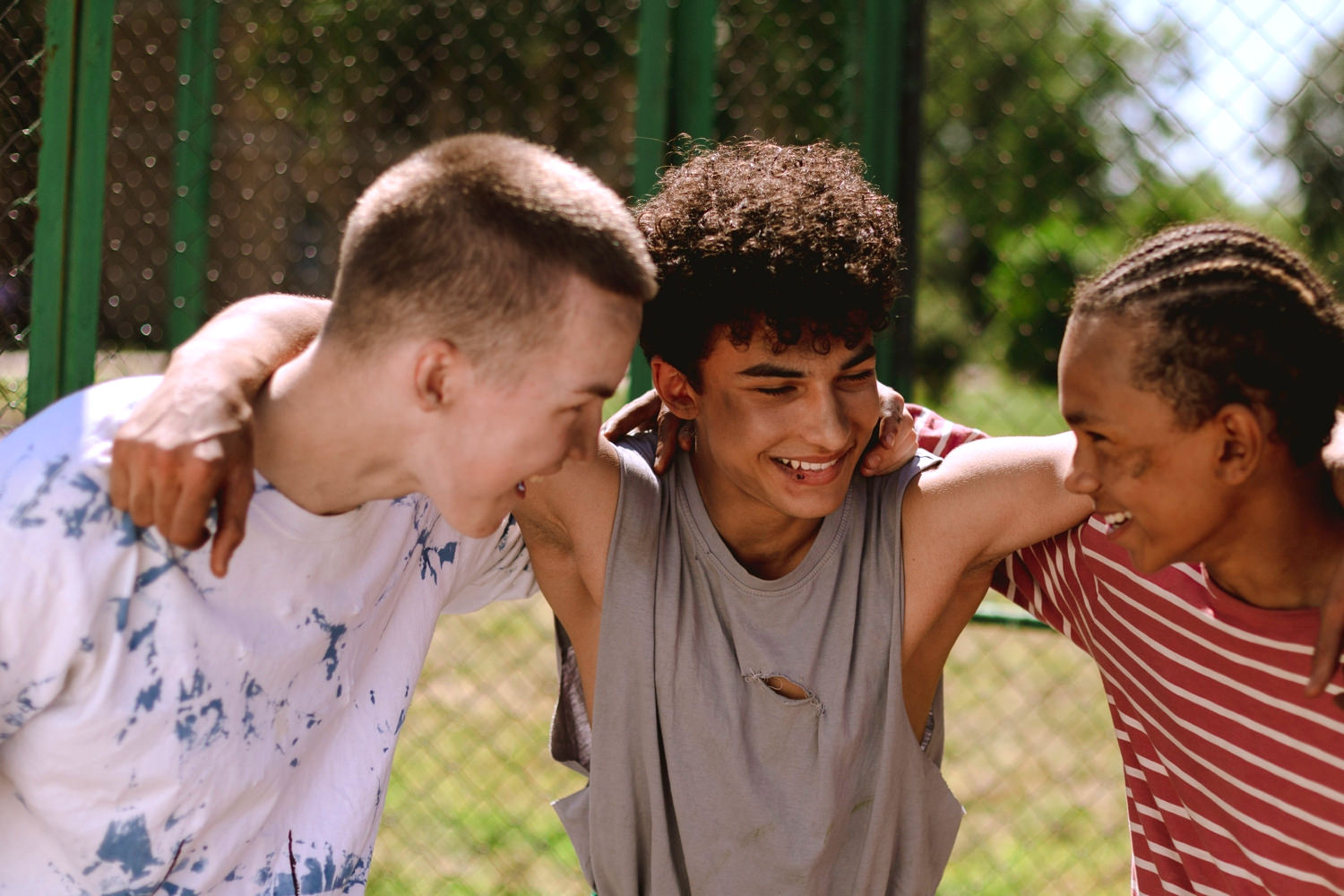 Bild zeigt: Drei Jugendliche unterschiedlicher Herkunft umarmen sich voller Freude