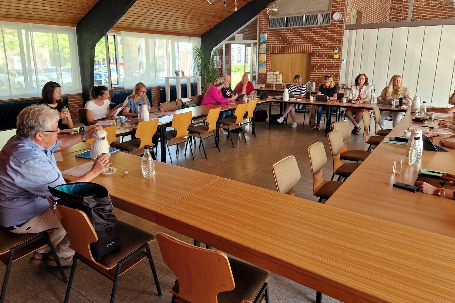 Bild zeigt: Verschiedene Personen sitzen zur Besprechung an Tischen