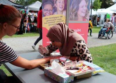 Bild zeigt: Am Stand erhält eine Besucherin auf ihre Hand ein Henna-Tatoo