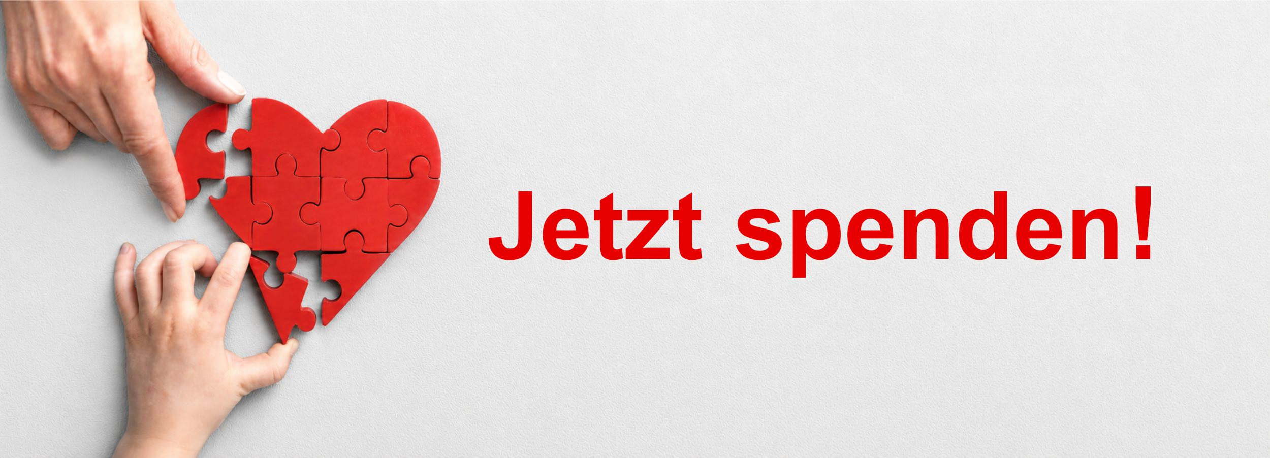 Zwei Hände legen ein Holz-Puzzle in Form eines Herzens Bild zeigt: Zwei Hände legen ein Holz-Puzzle in Form eines Herzens. Dazu der Text: Jetzt spenden.