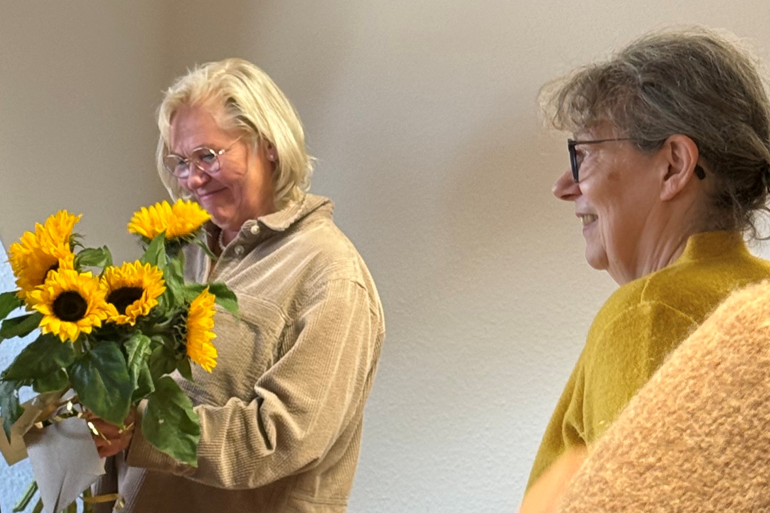 Bild zeigt: Links im Bild steht Gabriele Liesemann mit einem Strauß Sonnenblumen, der von Angelika Martin-Wild (rechts im Bild) überreicht wurde.